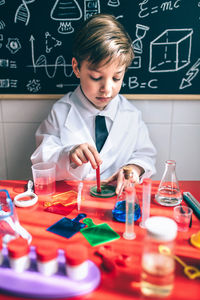 Boy wearing lap coat while sitting in classroom