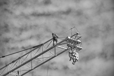 Low angle view of worker on crane against sky