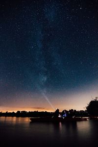 Boat in lake against star field at night