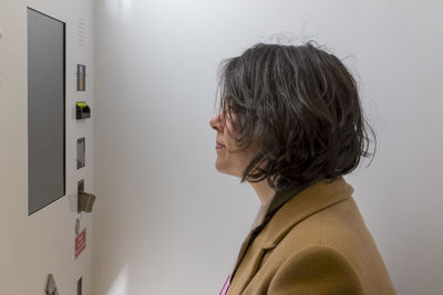 Side view of woman standing by machinery in wall