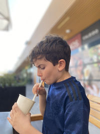 Kid drinking milkshake in outdoor cafe.