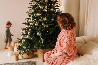 Side view of woman with christmas tree at home