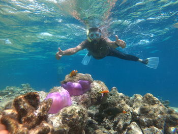 Man showing peace signs while snorkeling in sea