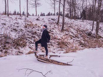 Side view of young man standing on frozen lake