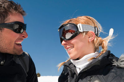 Close-up of smiling man and woman wearing ski goggles during winter