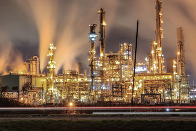 Illuminated factory against sky at night