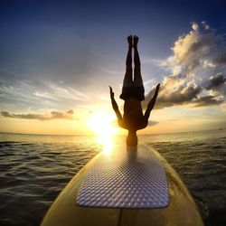 Man in sea against sky during sunset