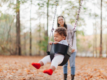 Mother and kids playing in park during autumn