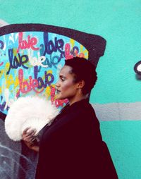 Side view of woman looking away against wall