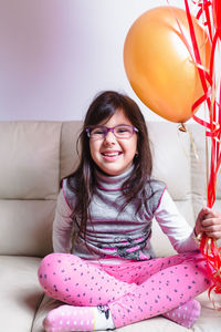 Portrait of smiling girl with balloons at home
