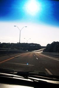 Cars moving on road against cloudy sky