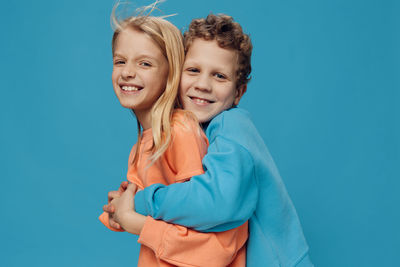 Happy brother and sister standing against blue background