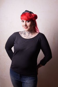 Portrait of smiling redhead woman standing against wall