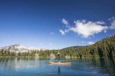 Man on riverbank against blue sky