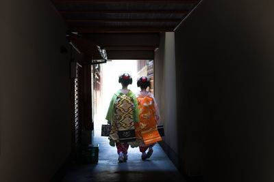 Rear view of people walking in corridor of building