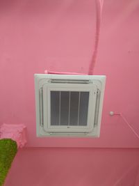 Close-up of electric lamp against pink wall