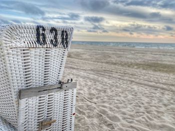 Hooded chairs on sand at beach against sky