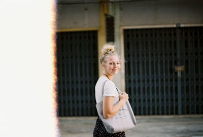 Portrait of young woman standing against wall