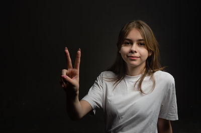 Portrait of young woman against black background