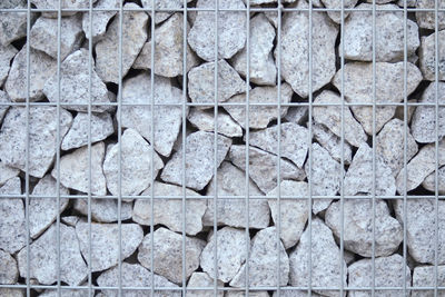 Full frame shot of a wall of stone contained by steel wires. 