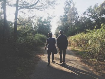 Rear view of two people walking in forest