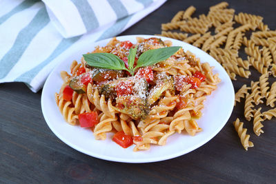 Plate of fresh cooked tasty and healthy wholemeal fusilli pasta in tomato sauce on kitchen table