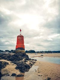 Lighthouse by sea against sky