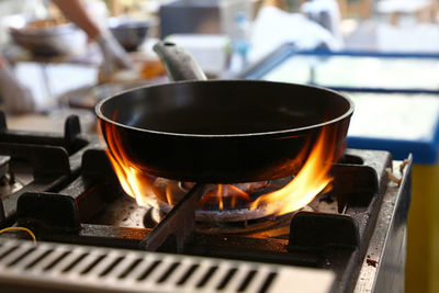 Close-up of cooking pan on burning stove at restaurant