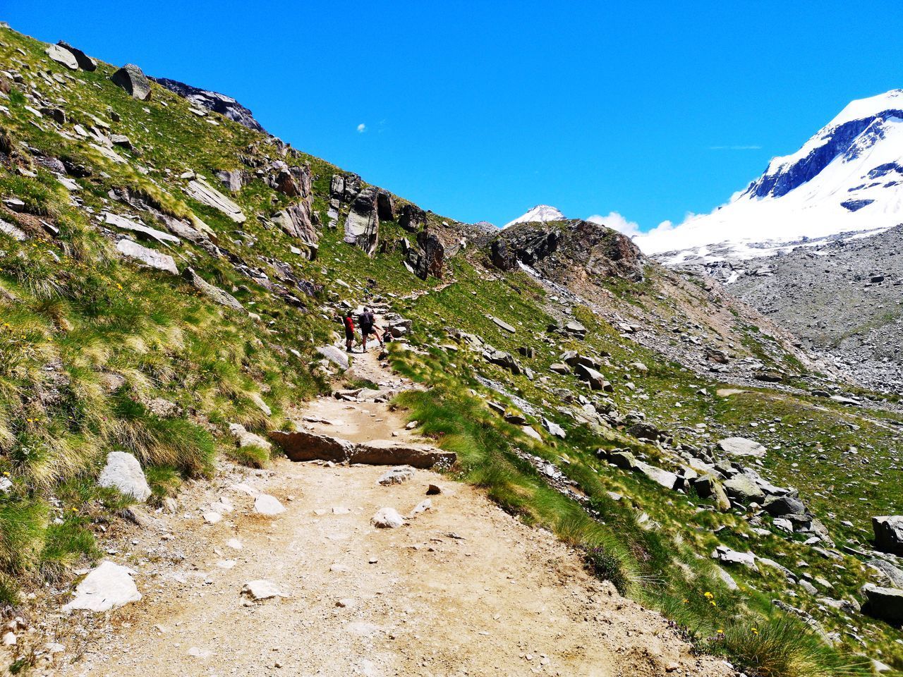 REAR VIEW OF MEN WALKING ON SNOWCAPPED MOUNTAIN AGAINST SKY