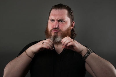 Portrait of man making face against black background