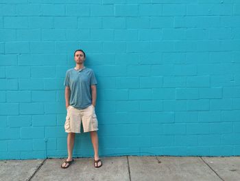 Portrait of man standing on blue wall