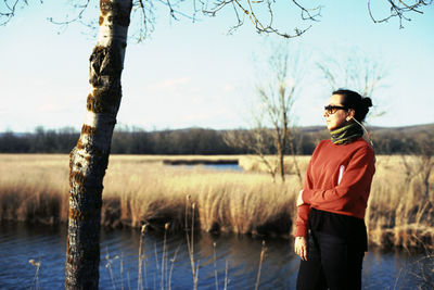 Young man standing by lake against sky