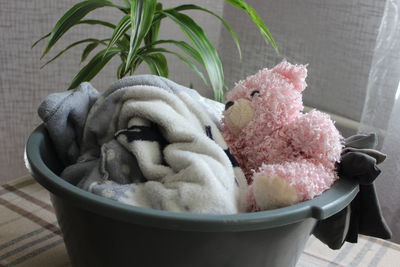 In the bathroom, next to the washing machine, there is a pink basket with dirty laundry.