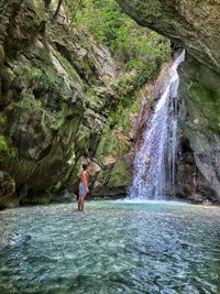 Full length of woman standing on rock in forest