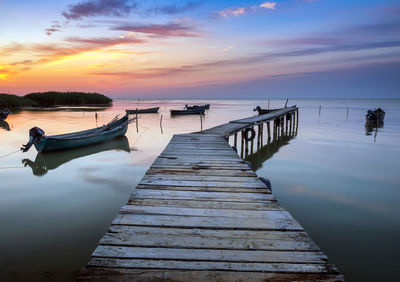 Pier over sea against sky during sunset