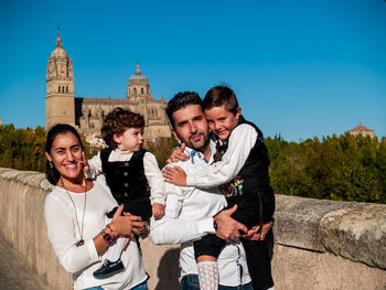 Portrait of happy family standing on road against clear blue sky