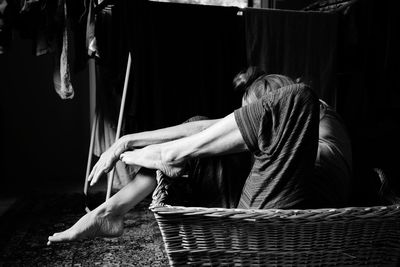 Side view of woman sitting on wicker basket