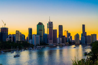 Sea by buildings against clear sky during sunset