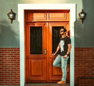Full length of young man standing by closed door