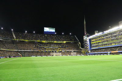 Group of people on soccer field against sky at night