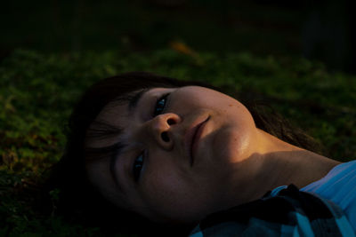 Close-up portrait of young woman lying in park