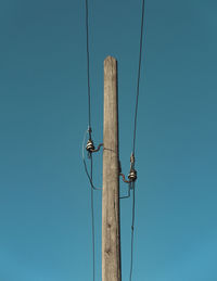 Low angle view of telephone pole against blue sky