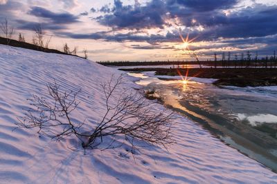 Frozen lake against sky during sunset