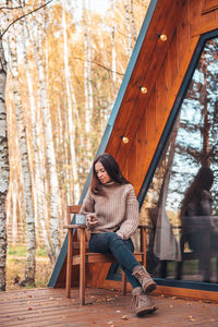 Woman sitting on mobile phone in forest