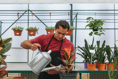 Young man standing by potted plants