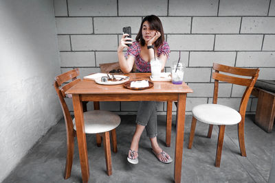 Full length of woman sitting on table at cafe