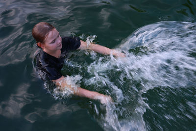 The girl swims in the pool and creates beautiful splashes on the dark water.