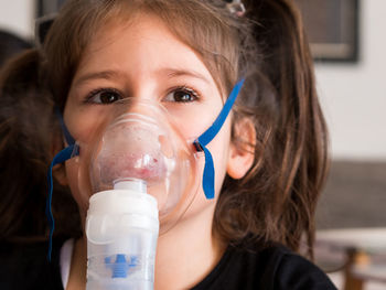 Cute girl wearing oxygen mask in clinic