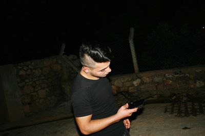 Young man using mobile phone at night
