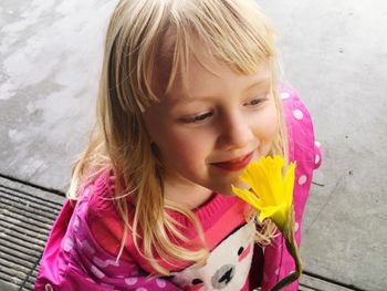 Close-up of smiling girl with yellow daffodil standing on footpath